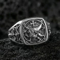 Load image into Gallery viewer, Sterling silver Lion of Judah signet ring with an oxidized finish, square face featuring a crowned lion beneath a cross and surrounding heraldic details, macro on black volcanic rock
