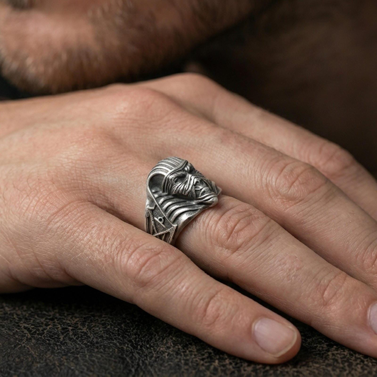 Sterling silver mummy pharaoh mask ring worn on a finger, close-up lifestyle shot highlighting the oxidized horror-inspired Egyptian face and ribbed headdress details