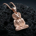 Load image into Gallery viewer, Sterling silver Egyptian spiritual pendant with a rose gold plated finish, Khnum ram-headed meditation figure with carved robe folds, close-up on black volcanic rock

