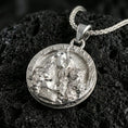 Load image into Gallery viewer, Sterling silver Freya pendant in a polished silver finish, round Norse goddess coin medallion with detailed hair and feline motif, macro on volcanic stone
