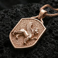 Load image into Gallery viewer, Sterling silver winged lion crest pendant with a rose gold plated finish, shield-shaped heraldic lion with wings in high relief, macro on black volcanic rock
