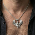 Load image into Gallery viewer, Sterling silver winged Egyptian cat pendant necklace on the neck, macro lifestyle image showing the polished silver finish and sculpted feline features
