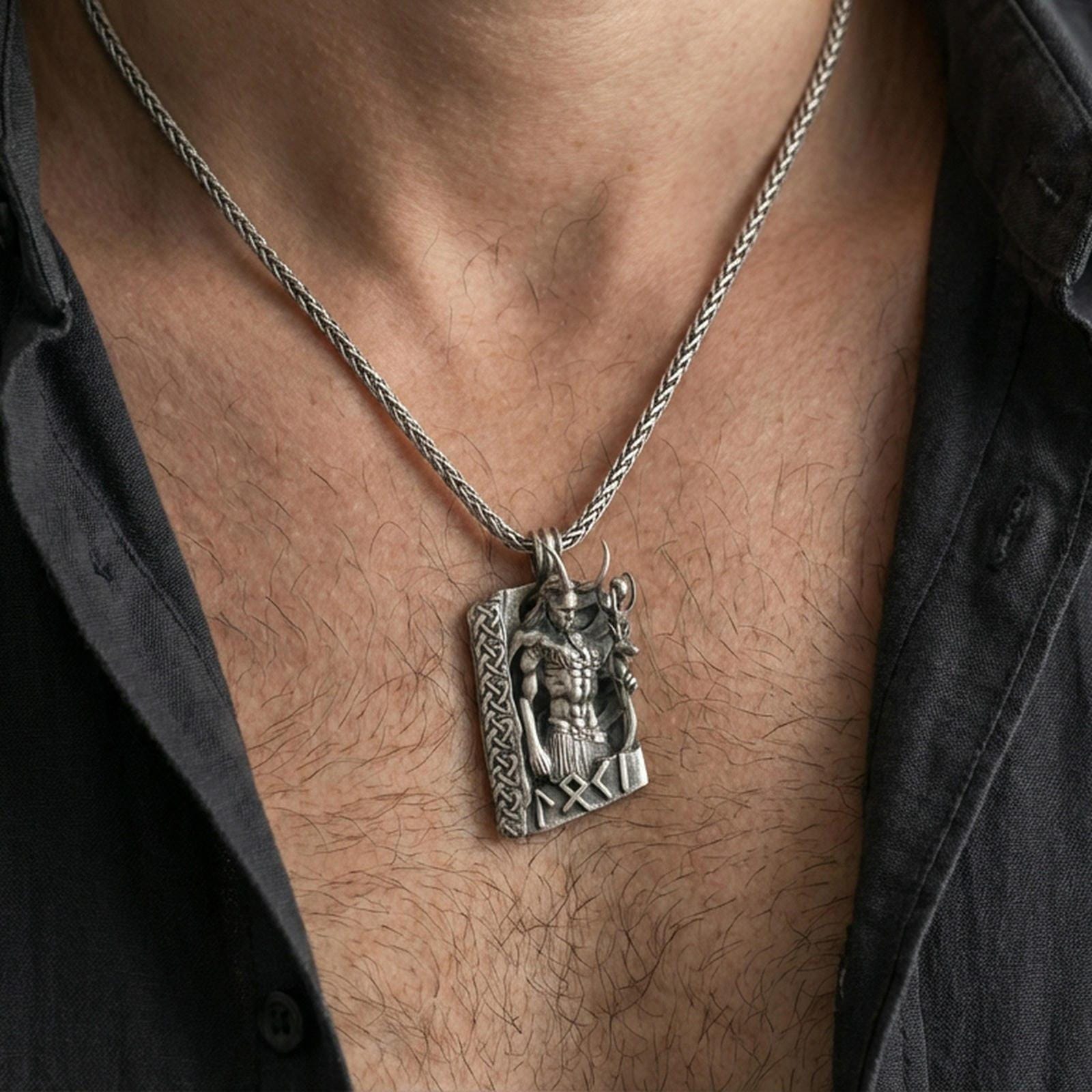 Oxidized Loki pendant necklace worn on the neck, lifestyle framing showing realistic scale and bold darkened detailing against the chest.