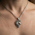 Load image into Gallery viewer, Oxidized unicorn head pendant necklace worn on the neck, lifestyle framing showing realistic scale and darkened vintage contrast against the chest.
