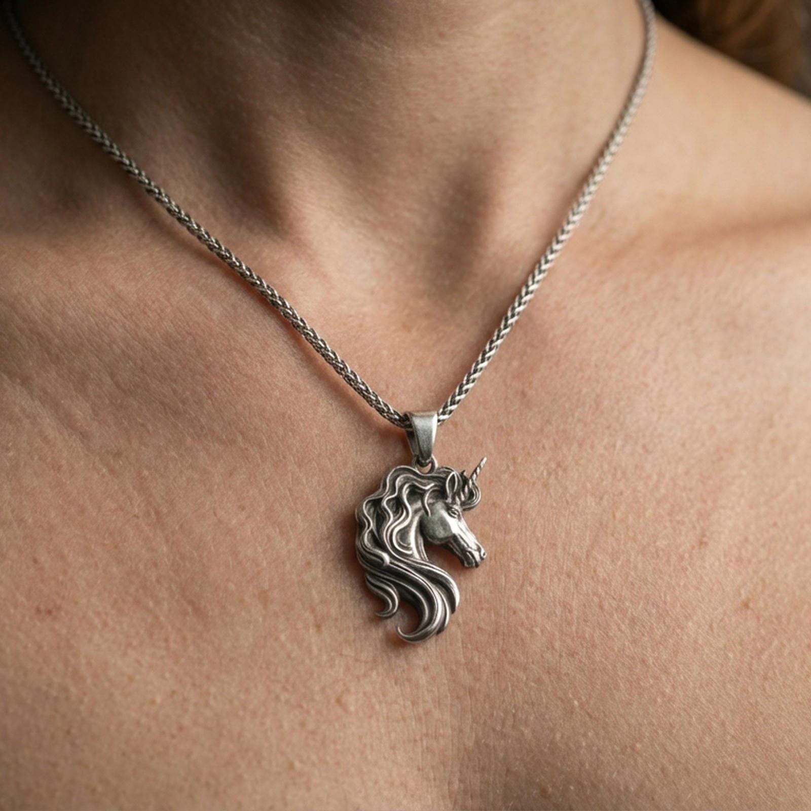 Oxidized unicorn head pendant necklace worn on the neck, lifestyle framing showing realistic scale and darkened vintage contrast against the chest.