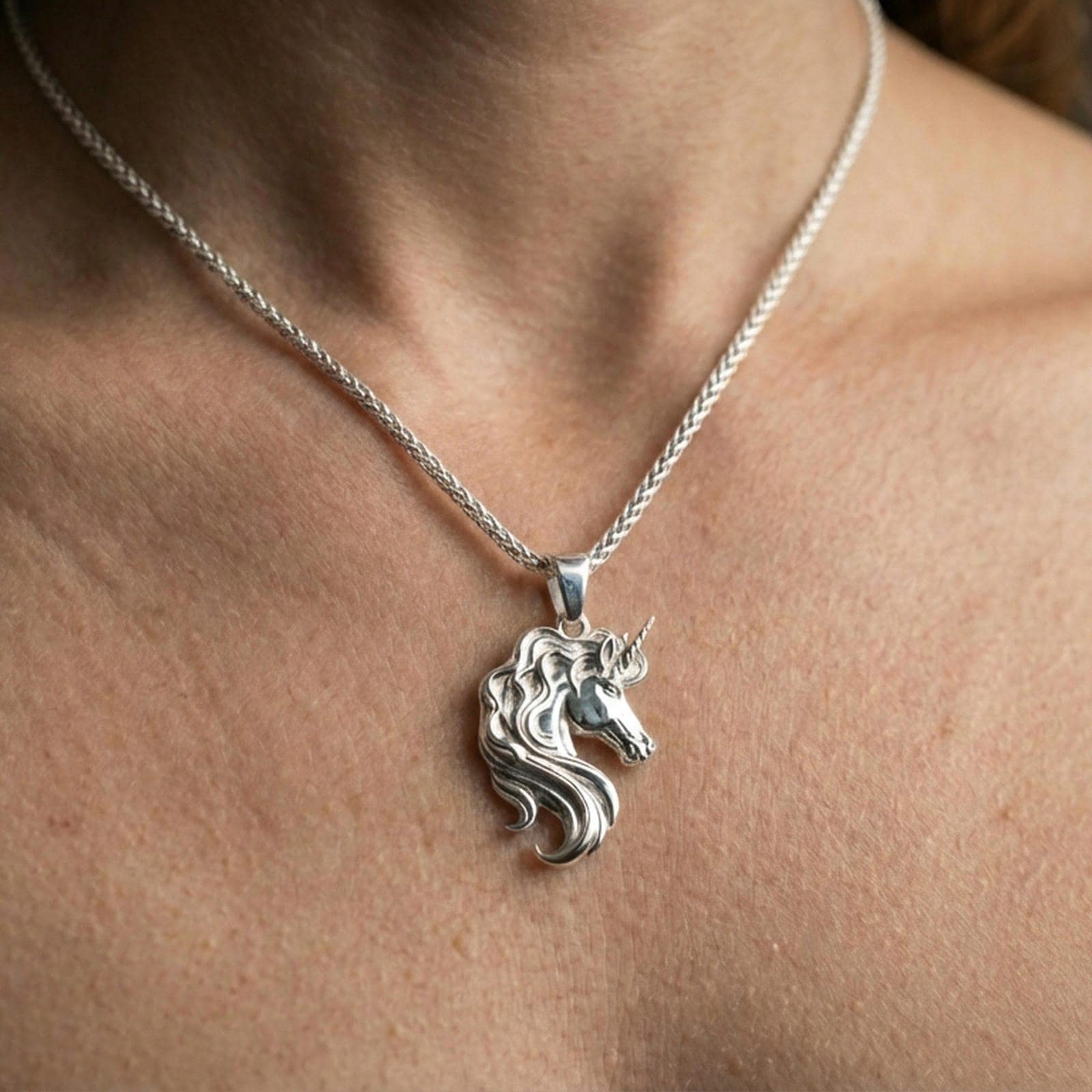 Polished silver unicorn head pendant necklace worn on the neck, clean lifestyle wear shot capturing bright shine and the detailed unicorn silhouette.