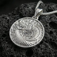 Load image into Gallery viewer, Polished silver oriental dragon medallion pendant necklace on textured volcanic rock, crisp macro product photo emphasizing sharp relief, clean edges, and detailed cloud swirls.
