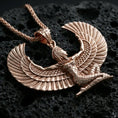 Load image into Gallery viewer, Rose gold plated winged goddess Isis pendant necklace on textured volcanic rock, centered studio-style close-up showcasing a soft rosy glow on the feathered wings and elegant goddess silhouette.
