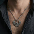 Load image into Gallery viewer, Oxidized winged goddess Isis pendant necklace worn on the neck, lifestyle framing showing realistic scale and bold vintage contrast against the chest.
