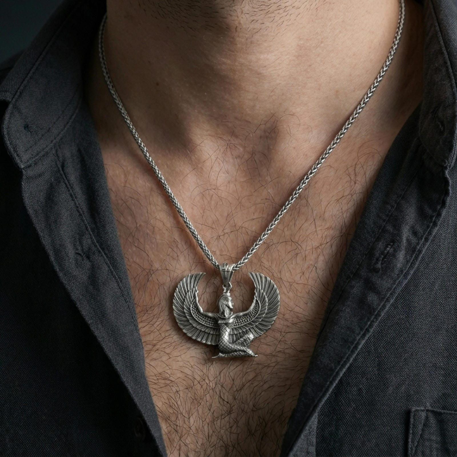 Oxidized winged goddess Isis pendant necklace worn on the neck, lifestyle framing showing realistic scale and bold vintage contrast against the chest.
