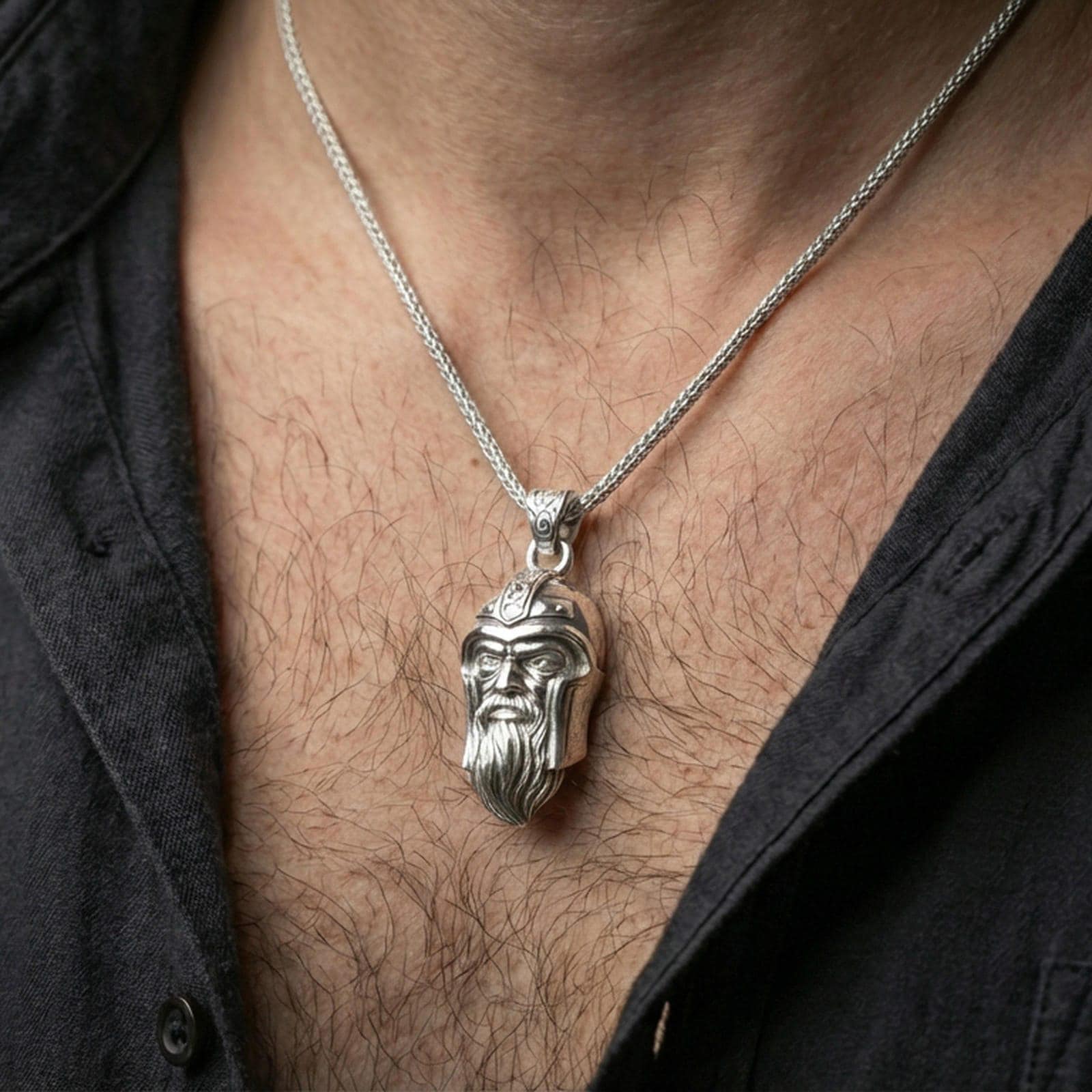 Polished silver Odin pendant necklace worn on the neck, clean lifestyle wear shot capturing bright shine and the detailed one-eyed warrior portrait in natural light.