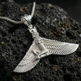 Load image into Gallery viewer, Polished silver winged goddess ankh pendant necklace on textured volcanic rock, crisp macro product photo emphasizing clean edges, sharp feather lines, and bright reflective highlights.
