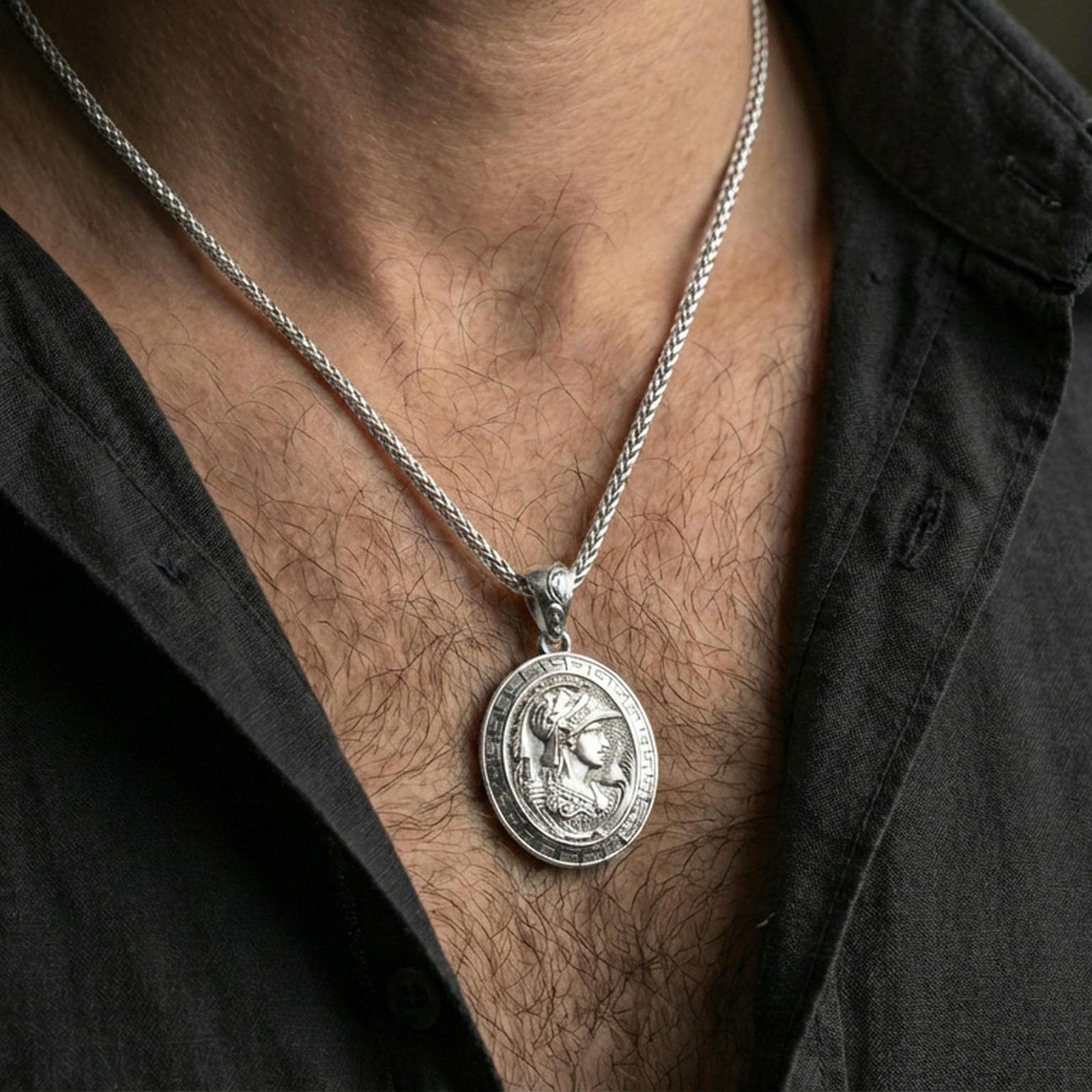 Polished silver Athena coin pendant necklace worn on the neck, clean lifestyle wear shot capturing bright shine and the detailed helmeted profile in natural light.