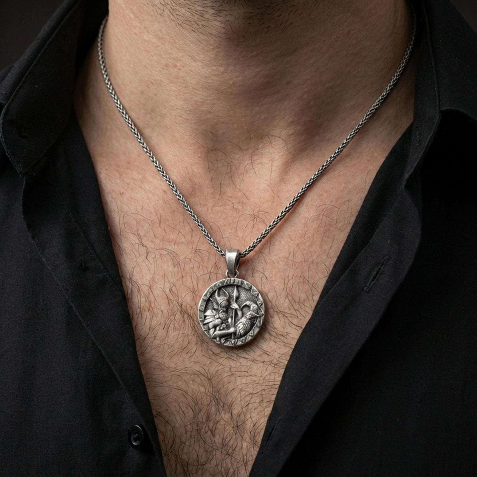 Oxidized Odin and raven medallion pendant necklace worn on the neck, lifestyle framing showing realistic scale and bold vintage contrast against the chest.