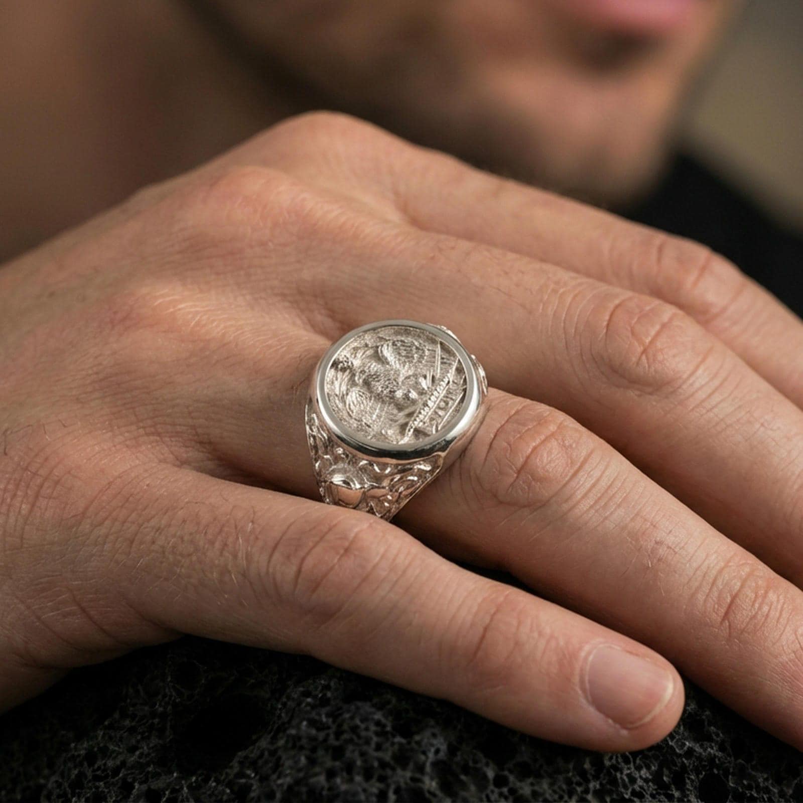 Polished silver SPQR coin style ring on textured volcanic stone, macro focus on the roman eagle emblem