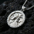 Load image into Gallery viewer, Polished silver Horus and Anubis pendant necklace on textured volcanic rock, crisp macro product photo emphasizing clean edges, sharp hieroglyph symbols, and bright reflective highlights on the relief.
