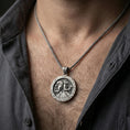 Load image into Gallery viewer, Oxidized Horus and Anubis pendant necklace worn on the neck, lifestyle framing showing realistic scale and bold vintage contrast against the chest.
