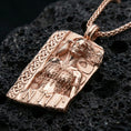 Load image into Gallery viewer, Rose gold plated Hel Norse goddess pendant necklace on textured volcanic rock, centered studio-style close-up showcasing soft rosy glow and intricate Norse relief detailing with clear rune accents.
