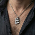 Load image into Gallery viewer, Polished silver Hel Norse goddess pendant necklace worn on the neck, clean lifestyle wear shot capturing bright shine and the detailed half-skull portrait relief in natural light.
