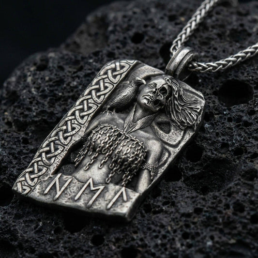 Oxidized Hel Norse goddess pendant necklace on textured volcanic rock, centered close-up highlighting the half-skull face, raven detail, rune accents, and deep antique shadowed contrast.