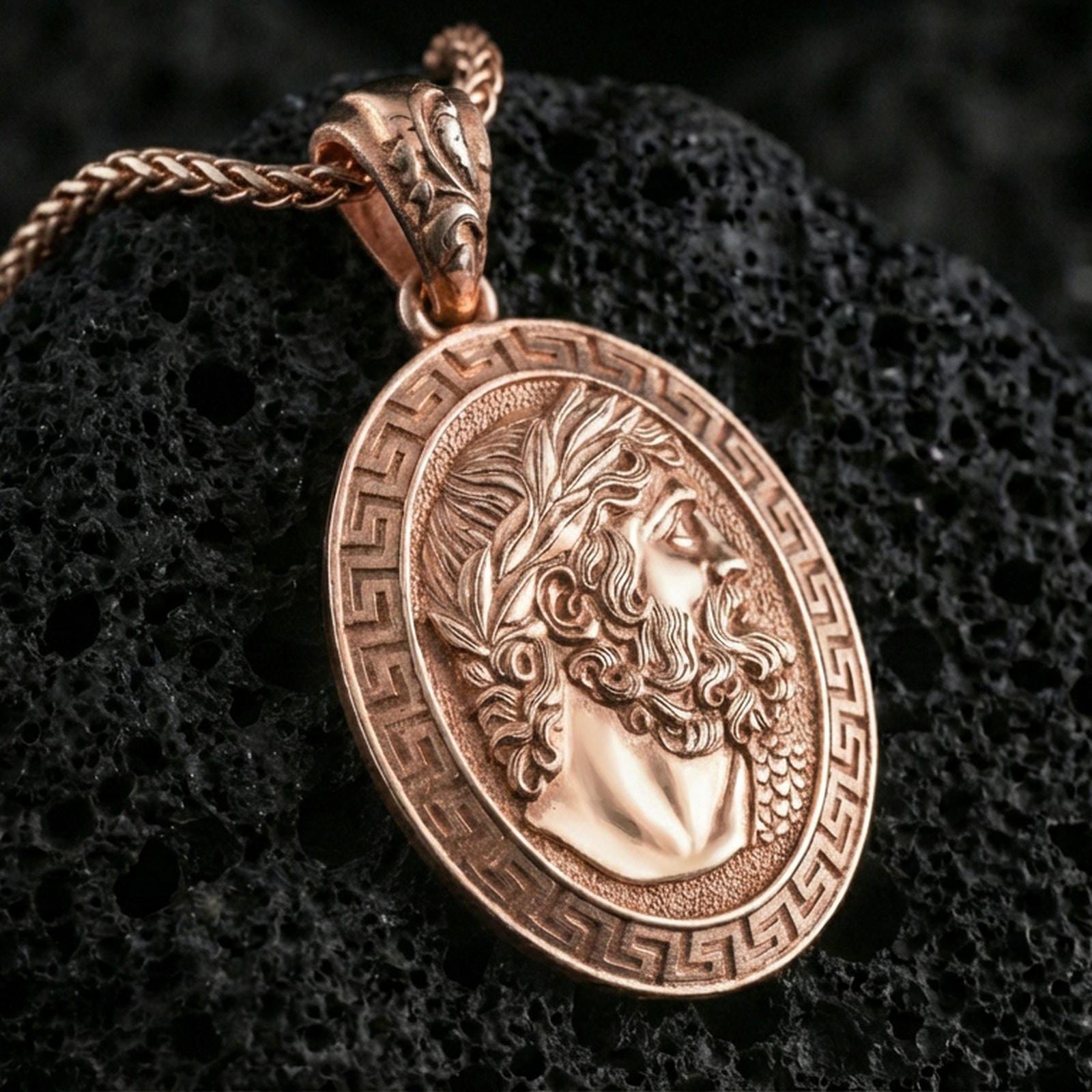 Rose gold plated Hades coin pendant necklace on textured volcanic rock, centered studio-style close-up showcasing soft rosy glow and intricate Greek mythology portrait detailing.