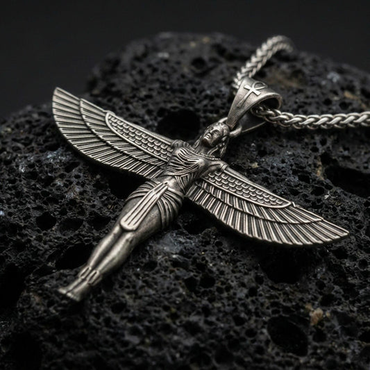 Oxidized winged Isis goddess pendant necklace on textured volcanic rock, centered close-up highlighting the spread wings, feather lines, and deep antique shadowed contrast.