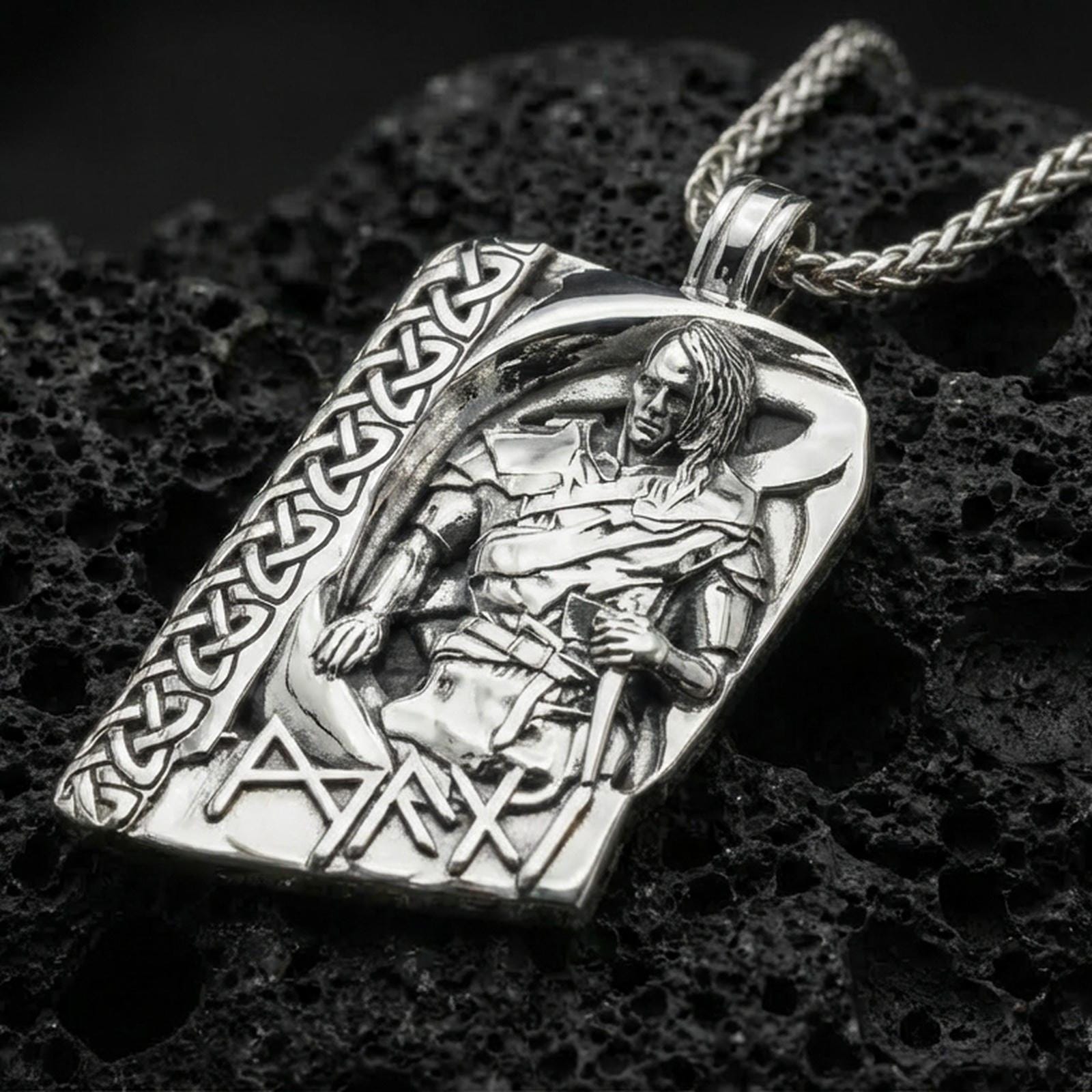 Polished silver Norse moon god pendant necklace on textured volcanic rock, crisp macro product photo emphasizing clean edges, sharp sculpted armor detail, and bright reflective highlights on the figure and runes.