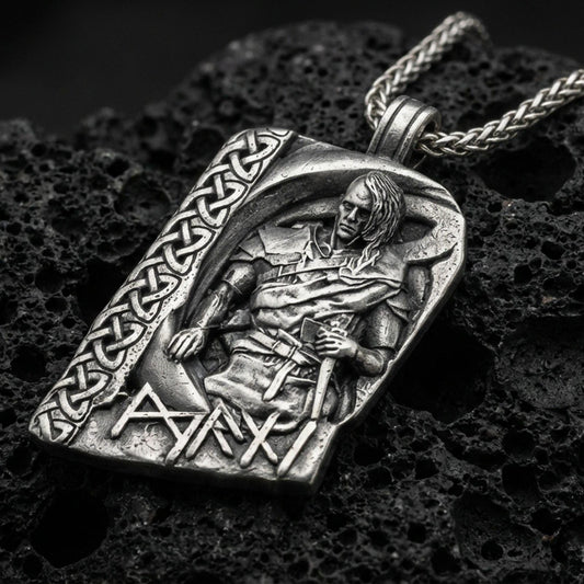 Oxidized Norse moon god pendant necklace on textured volcanic rock, centered close-up highlighting the seated deity relief, Celtic knot border, rune lettering, and deep antique shadowed contrast.