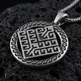 Load image into Gallery viewer, Oxidized geometric rune-style medallion pendant necklace on textured volcanic rock, centered close-up highlighting the raised maze-like symbol, patterned border, and deep antique shadowed contrast.
