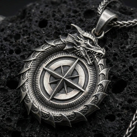 Oxidized sterling silver dragon compass pendant on porous volcanic rock, close-up showing the compass rose centerpiece