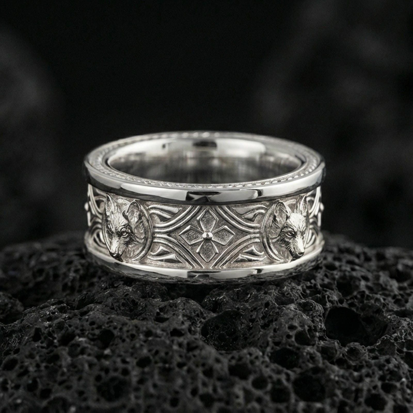 Polished silver fox band ring on textured volcanic rock, crisp macro product photo emphasizing clean edges, sharp relief detailing, and bright reflective highlights across the patterned band.