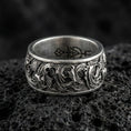 Load image into Gallery viewer, Oxidized koi fish band ring on textured volcanic rock, centered close-up highlighting the flowing koi relief, wave scrollwork, and deep antique shadowed contrast.
