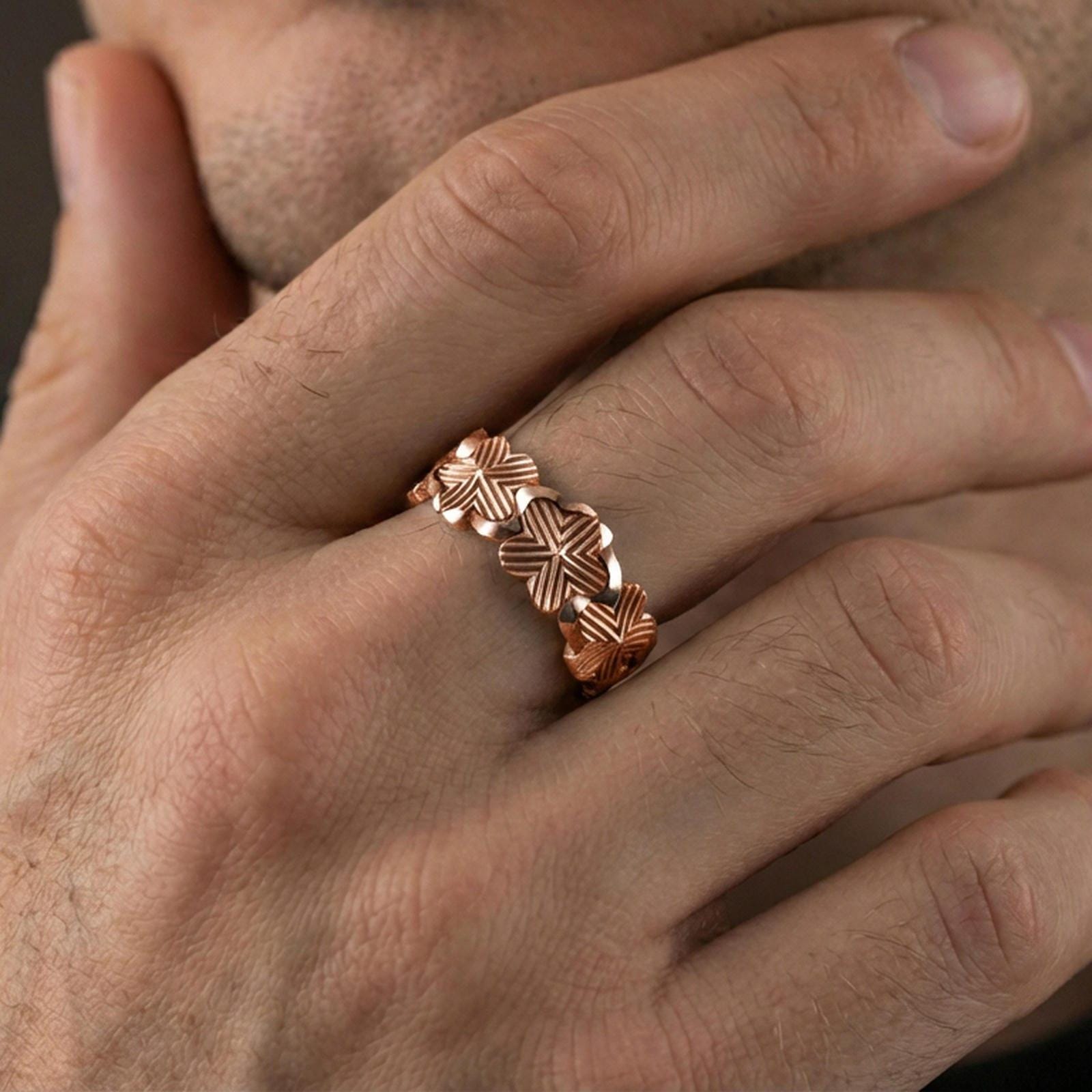Rose gold plated floral band ring worn on a finger, lifestyle wear shot with elegant rosy shine and crisp floral detailing visible.