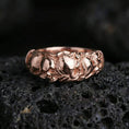 Load image into Gallery viewer, Rose gold plated skull band ring on textured volcanic rock, centered studio-style close-up showcasing soft rosy glow and crisp skull detailing with a refined finish.
