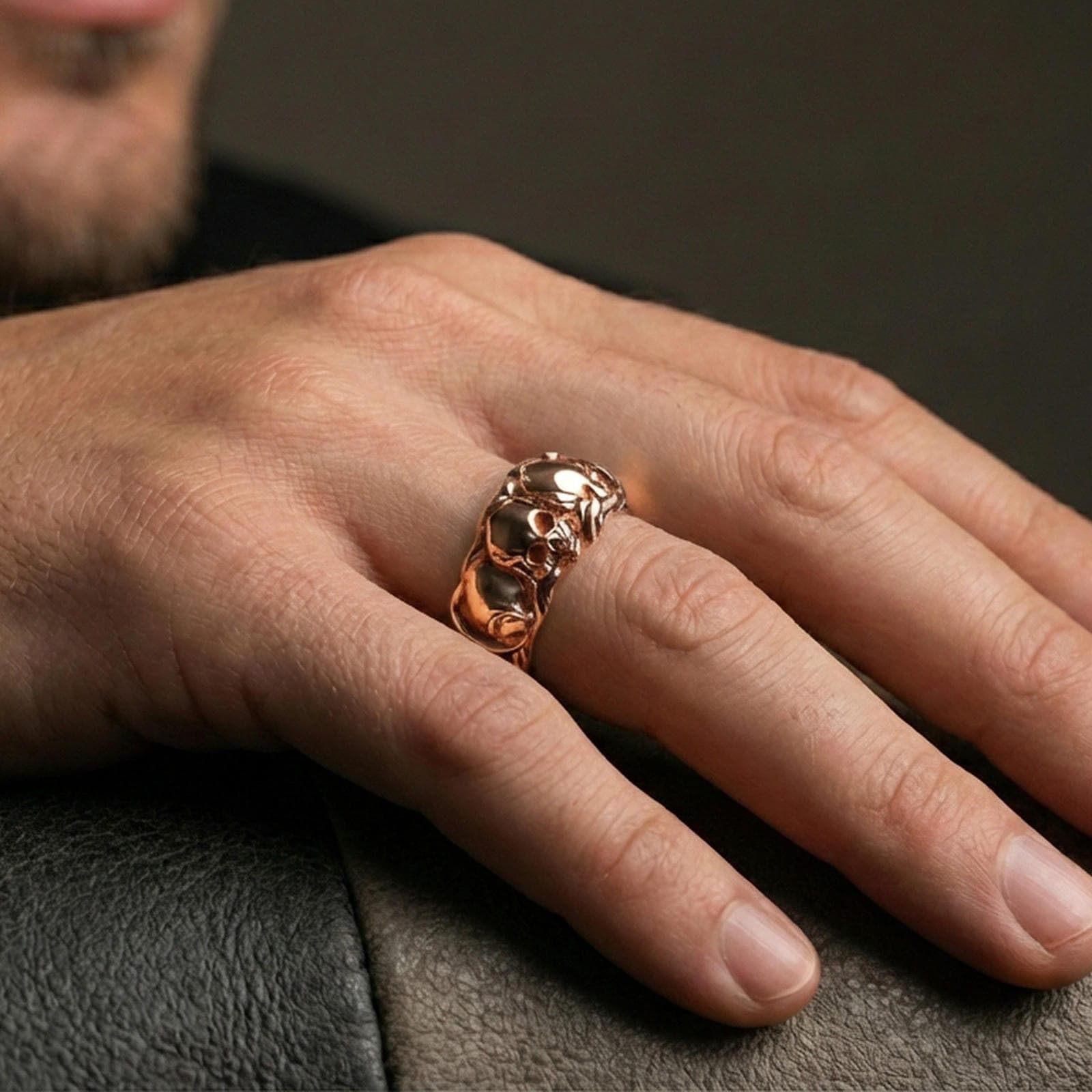 Rose gold plated skull band ring worn on a finger, lifestyle wear shot with elegant rosy shine and crisp skull detailing visible.