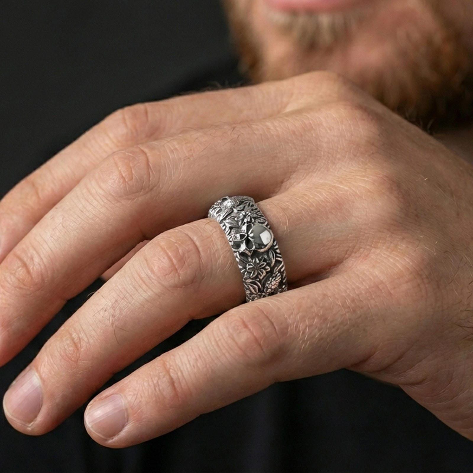 Polished silver skull and koi floral band ring worn on a finger, clean lifestyle wear shot capturing bright shine and the detailed skull-and-koi floral relief in natural light.