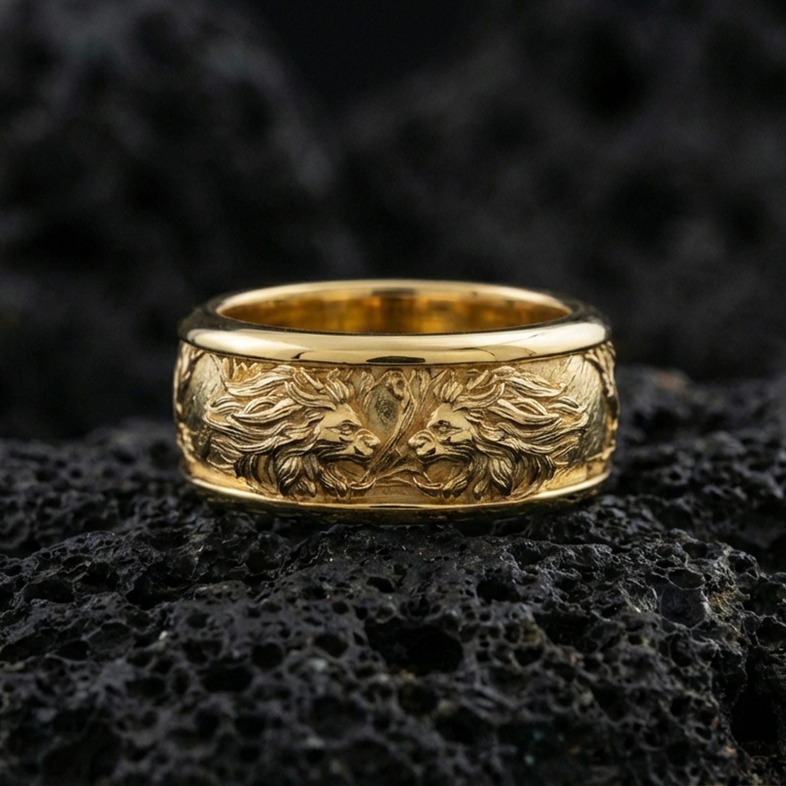 Gold plated twin lion band ring on textured volcanic rock, premium close-up with warm reflective shine across the lion profiles, raised contours, and detailed mane texture.