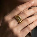 Load image into Gallery viewer, Gold plated face relief band ring worn on a finger, lifestyle photo featuring warm tone finish and strong statement band presence.
