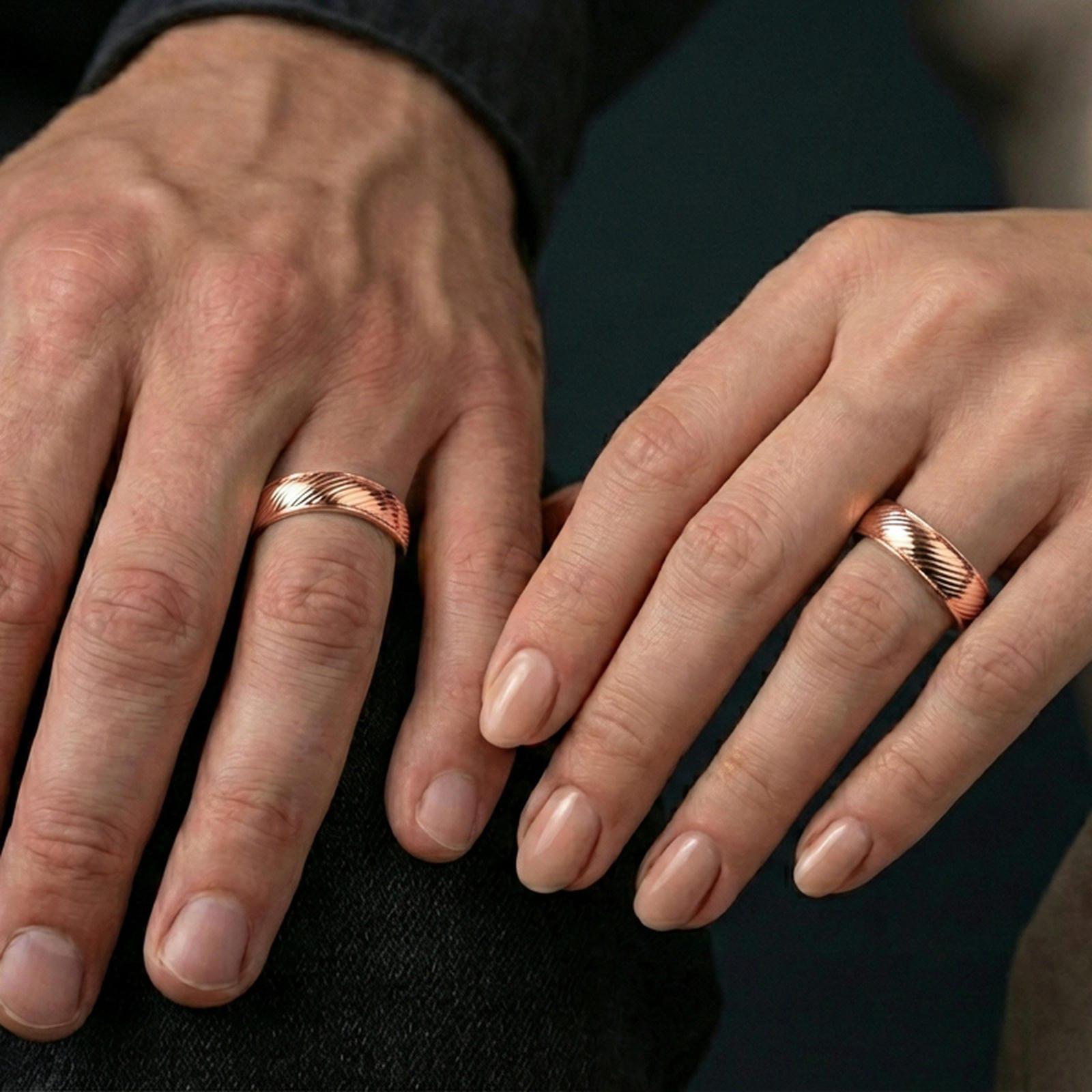 Rose gold plated diagonal groove band ring worn on a finger, lifestyle wear shot with elegant rosy shine and crisp diagonal groove detailing visible.