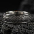 Load image into Gallery viewer, Oxidized woven texture band ring on textured volcanic rock, macro close-up highlighting the darkened braided pattern and antique silver contrast.
