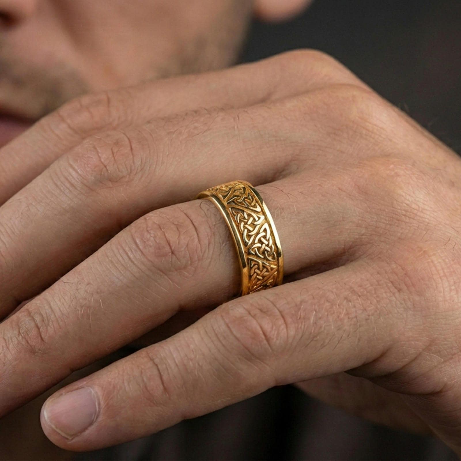 Gold plated Celtic knot band ring worn on a finger, lifestyle wear shot capturing warm reflective finish and clear visibility of the knot design.