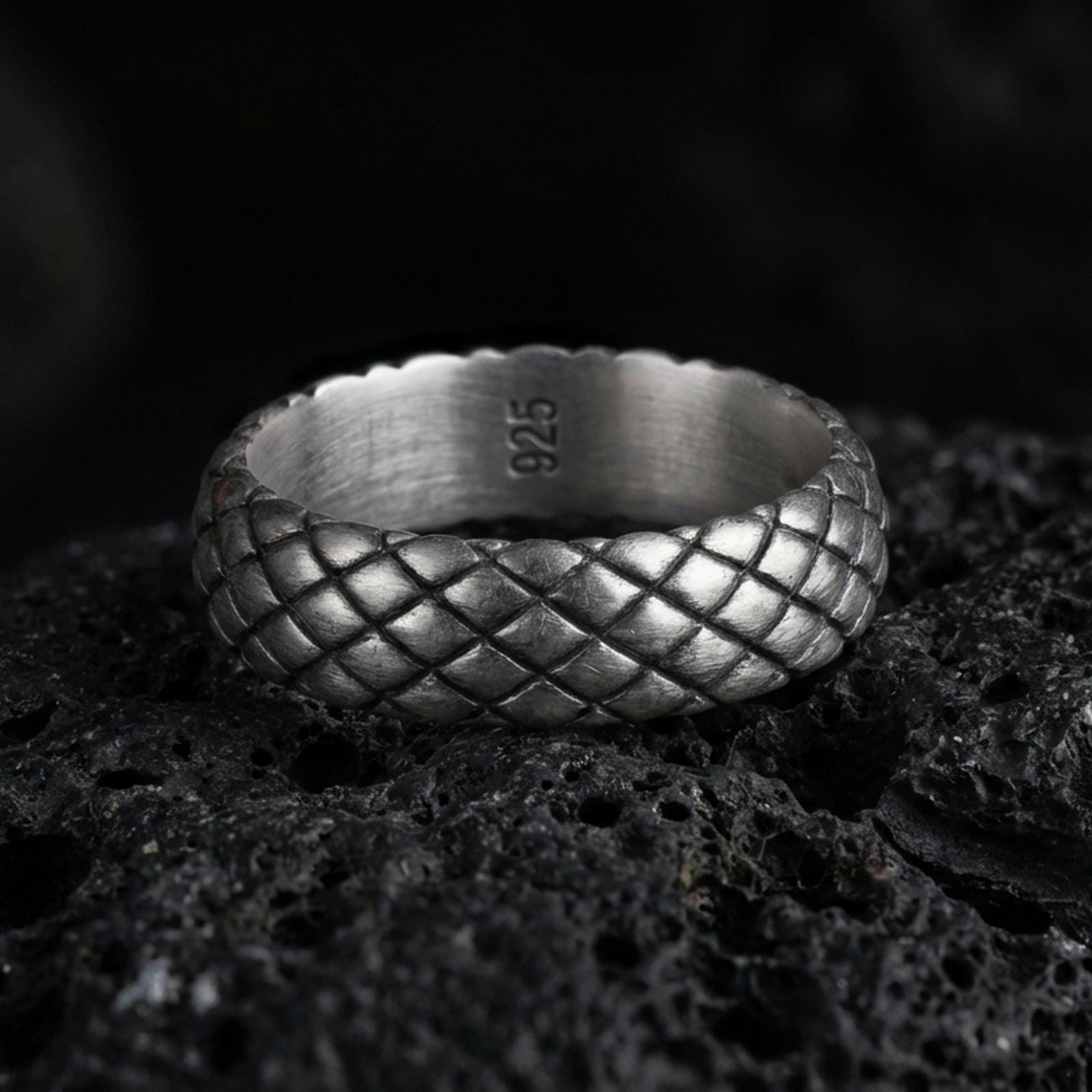 Oxidized woven texture band ring on volcanic stone, macro close-up showing darkened grooves and raised basketweave pattern depth.
