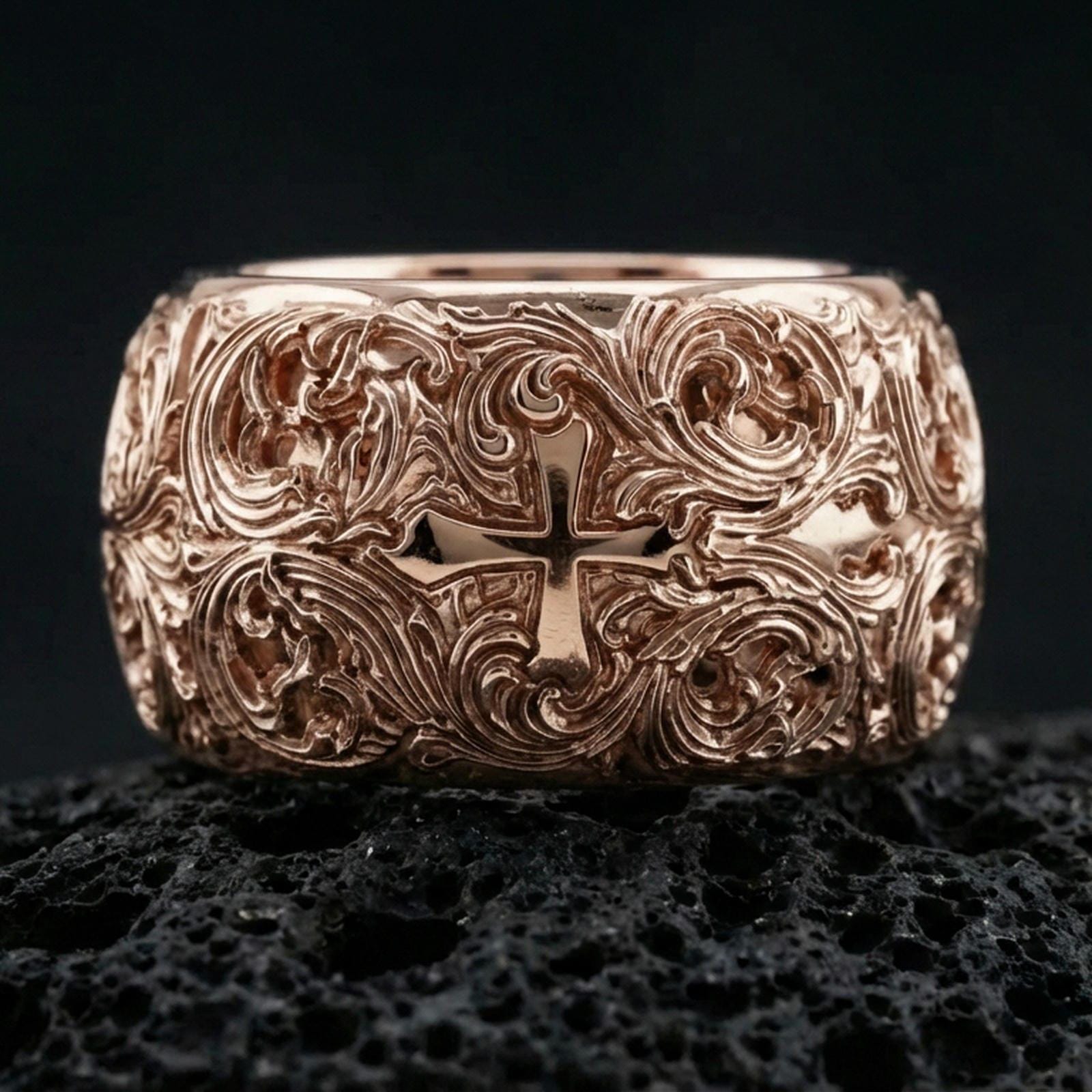 Rose gold plated ornate cross band ring on volcanic stone, refined macro shot capturing soft rose highlights on the cross centerpiece and ornate scroll detailing.