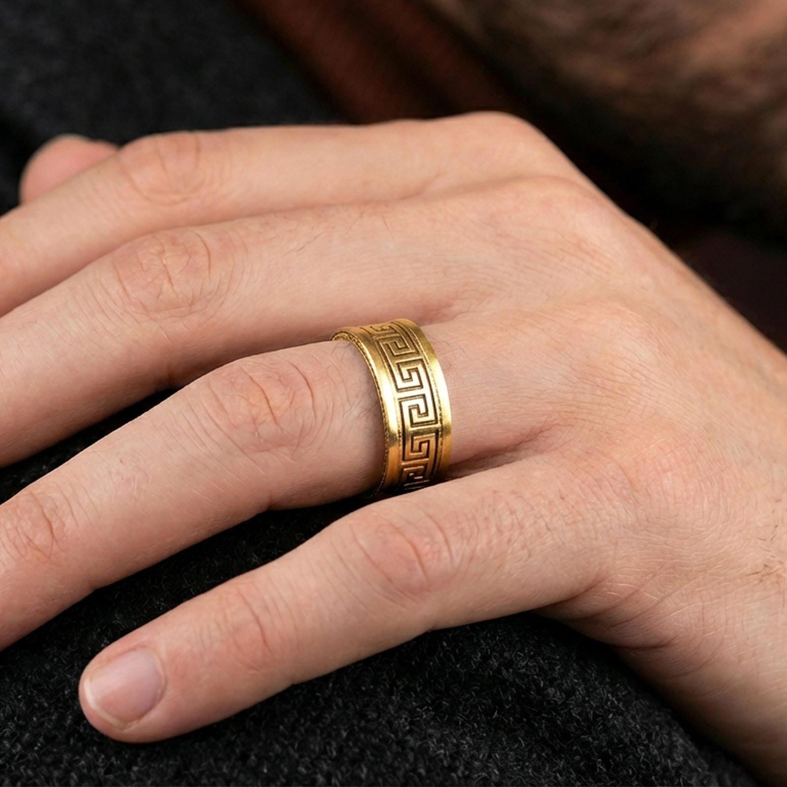 Gold plated Greek key spinner ring worn on a finger, lifestyle wear shot highlighting luxury gold tone, geometric Greek key symbolism, and smooth spinner function.