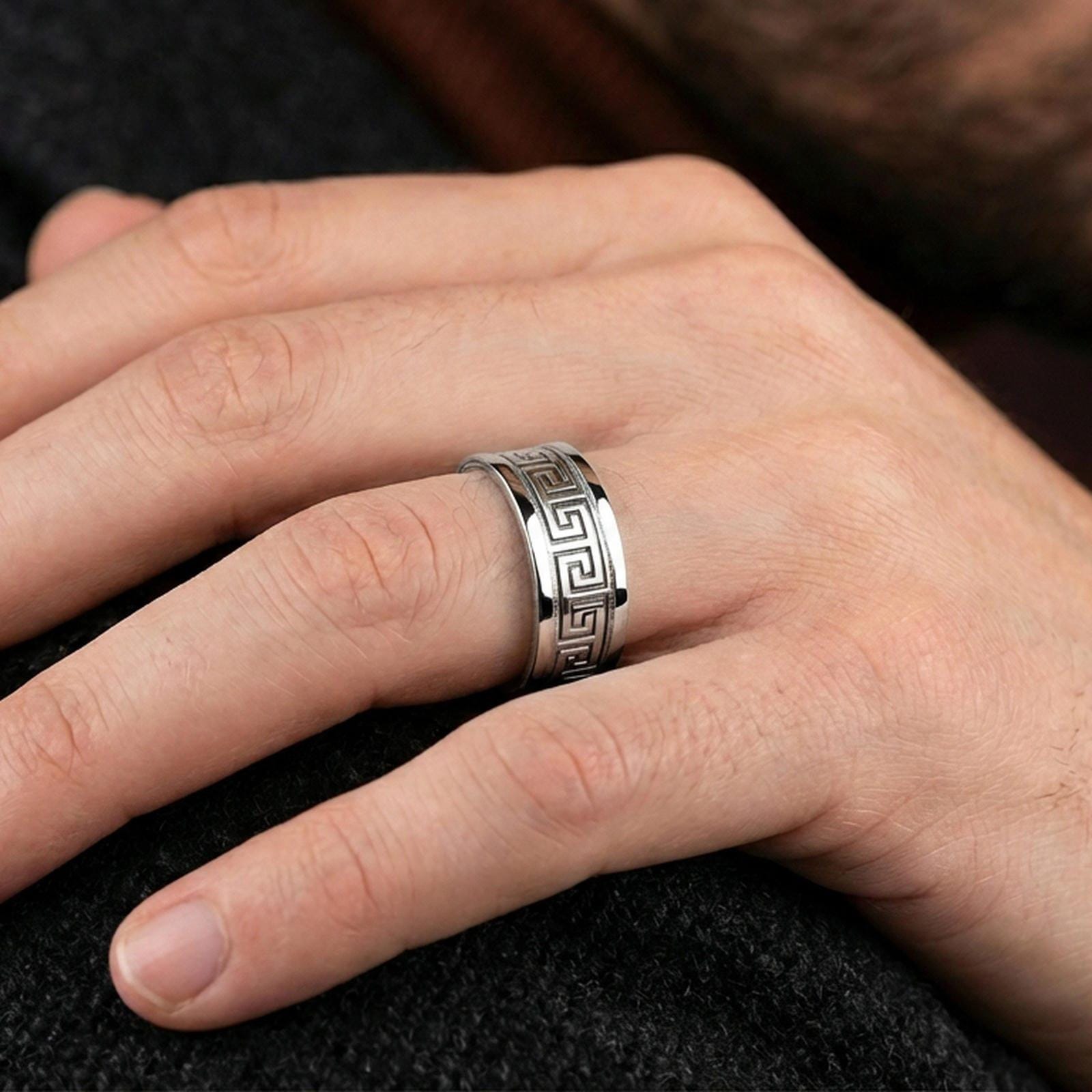 Polished silver Greek key spinner ring worn on a finger, lifestyle photo showcasing sleek modern shine and the continuous meander pattern in motion.