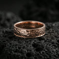 Load image into Gallery viewer, Rose gold plated hammered texture band ring on volcanic stone, elegant macro shot capturing soft rose reflections over the hammered detailing and rounded profile.

