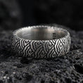Load image into Gallery viewer, Oxidized sterling silver wave pattern band ring on volcanic stone, macro close-up highlighting deepened grooves, textured contrast, and vintage character.
