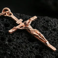 Load image into Gallery viewer, Rose gold plated crucifix pendant on volcanic stone, elegant macro shot capturing soft rose reflections, refined contours, and high-relief craftsmanship.
