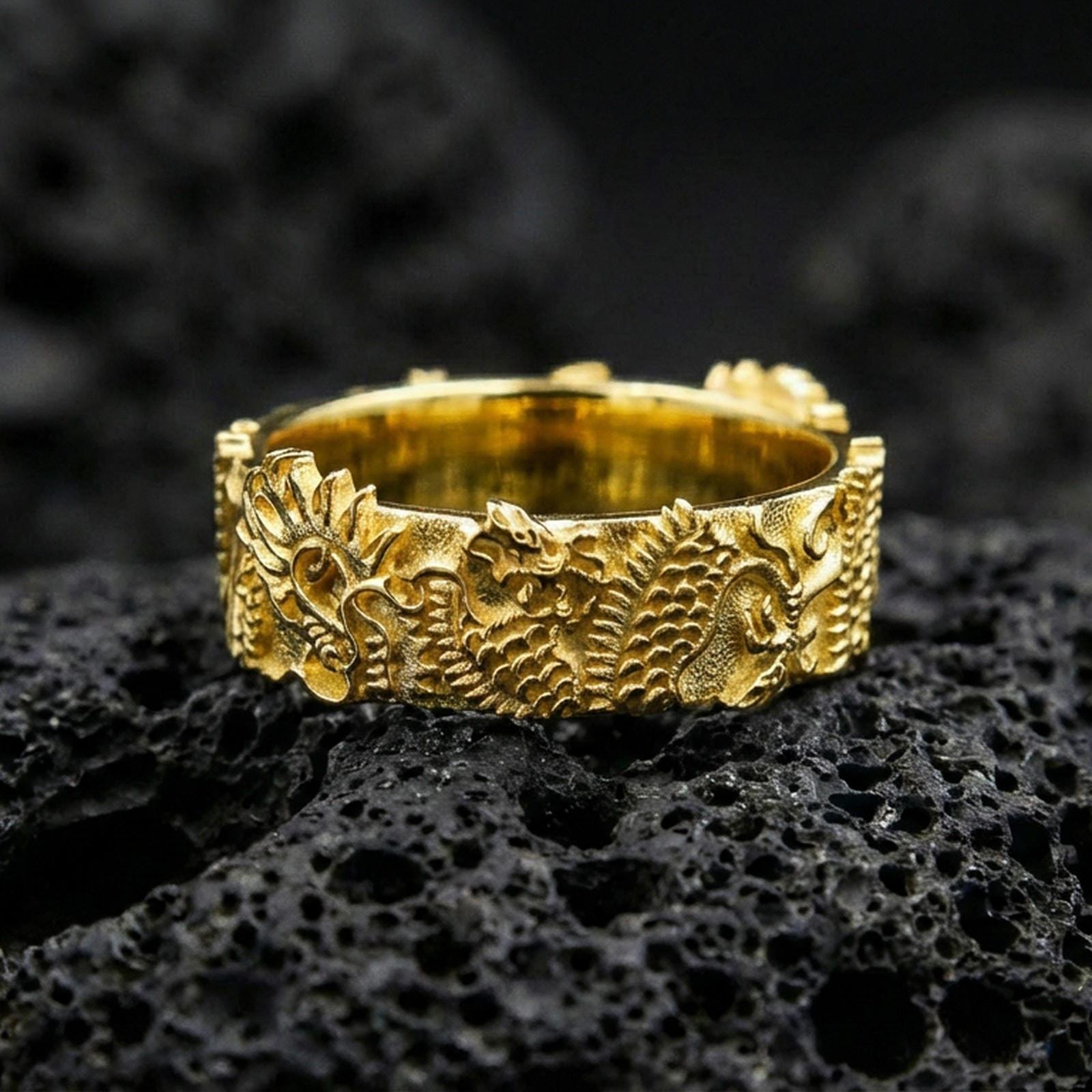Gold plated Japanese dragon band ring on volcanic stone, premium macro close-up showcasing warm gold tone across the dragon motif and sculpted texture.