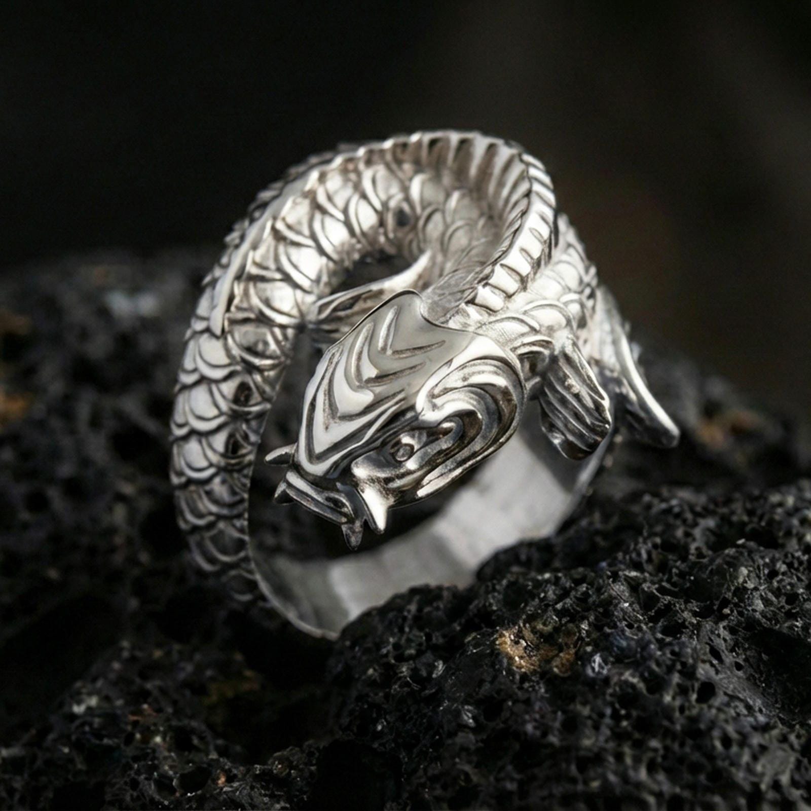 Polished silver koi fish wrap ring on volcanic stone, macro shot emphasizing smooth reflective surfaces, crisp sculpting, and clean scale definition.